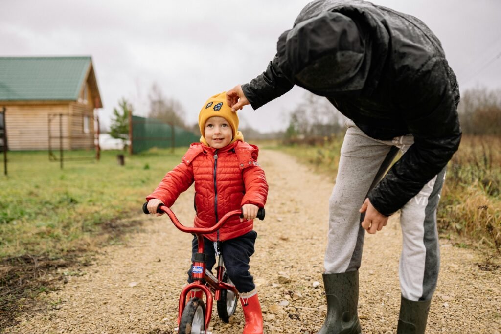 Father teaching his son how to ride a bike on a dirt path.