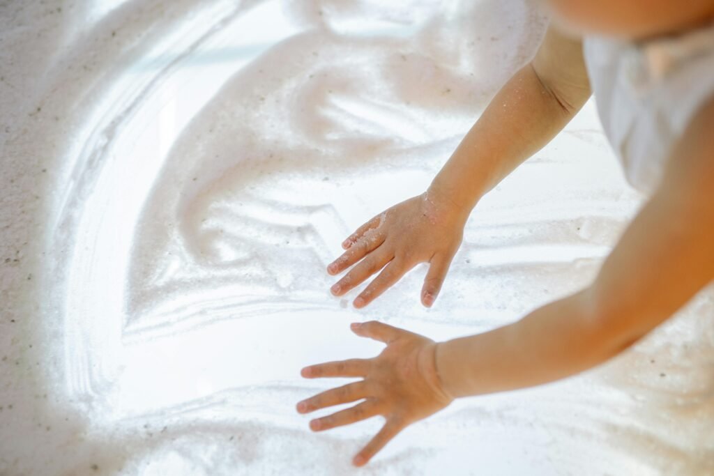 Toddler playing with a sensory bin filled with sand